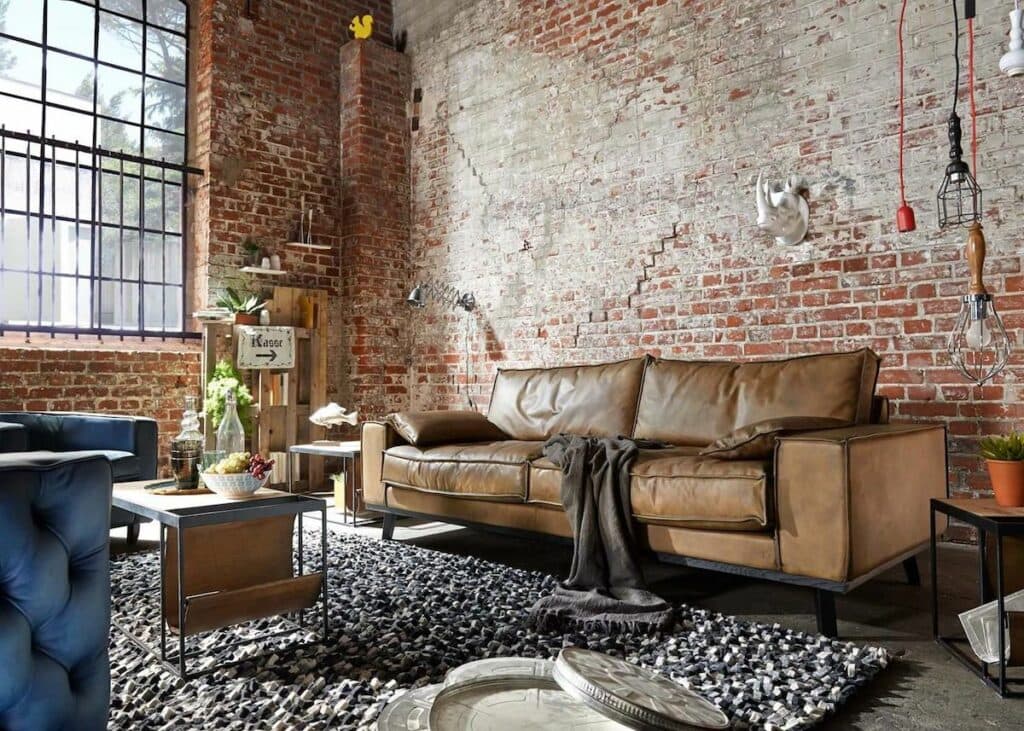 salon industriel mur brique rouge canapé cuir marron suspension métal noir