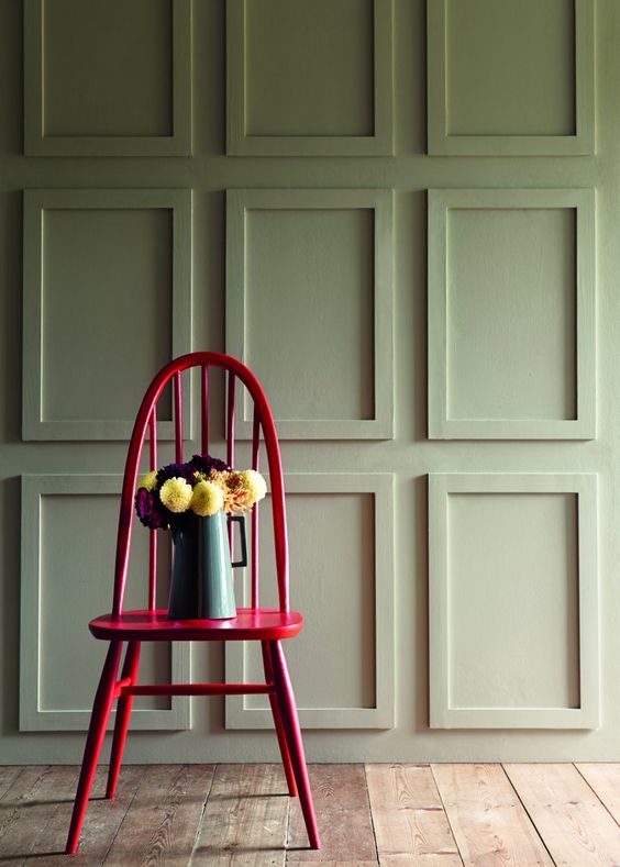 chaise rose flashy et mur vert kaki