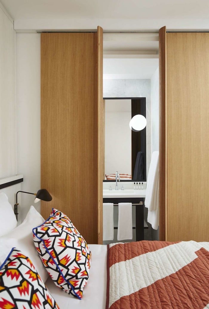 appart parisien toit vue salle de bain blanc et noir linge de lit graphique portes coulissante en bois petite salle d'eau prive