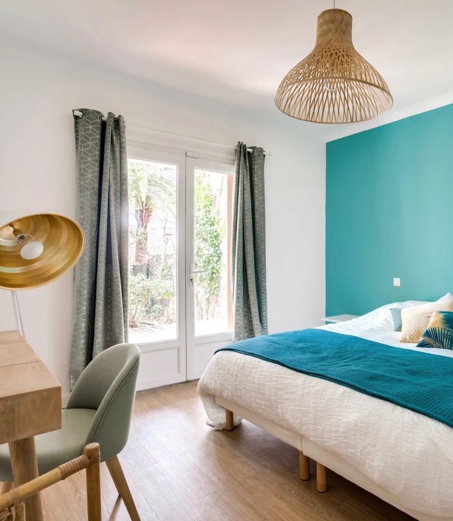 chambre spacieuse mur bleu baie vitrée vue sur jardin suspension luminaire rotin parquet bois - blog déco - clemaroundthecorner