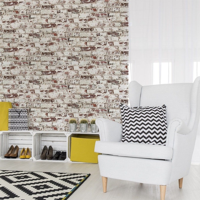 salon scandinave industriel mur briques rouges effacées fauteuil gris clair tapis coussin noir et blanc géométrique