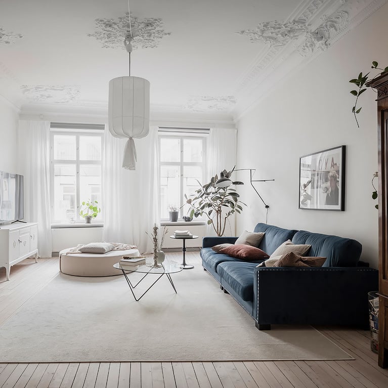 salon spacieux parquet en bois clair canapé bleu velours table basse verre pied métallique noire