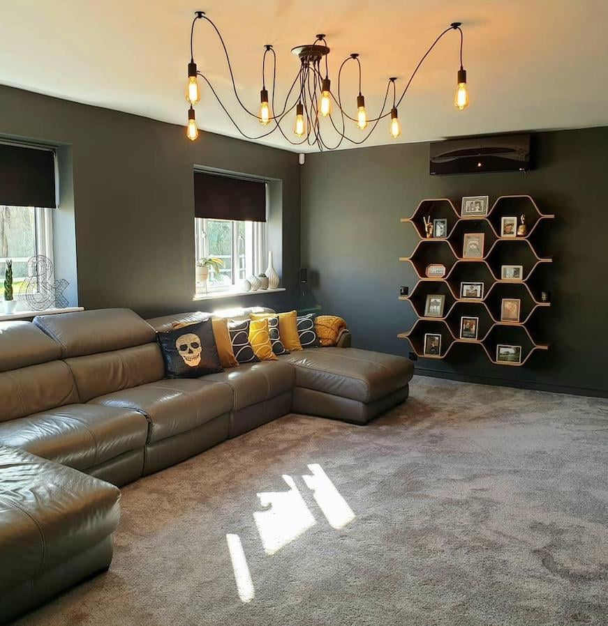 bibliothèque originale oval fixée au mur sol moquette grise canapé cuir déco salon