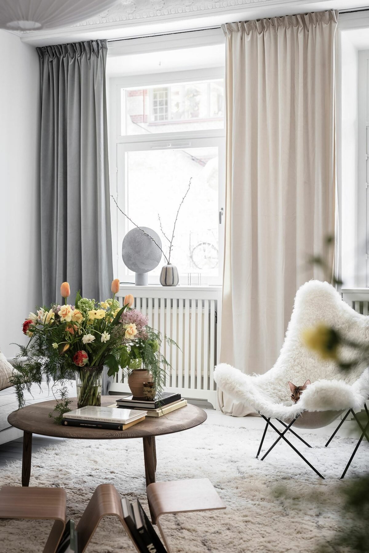 salon blanc table basse bois foncé rideaux gris foncé rose fauteuil papillon moumoutte