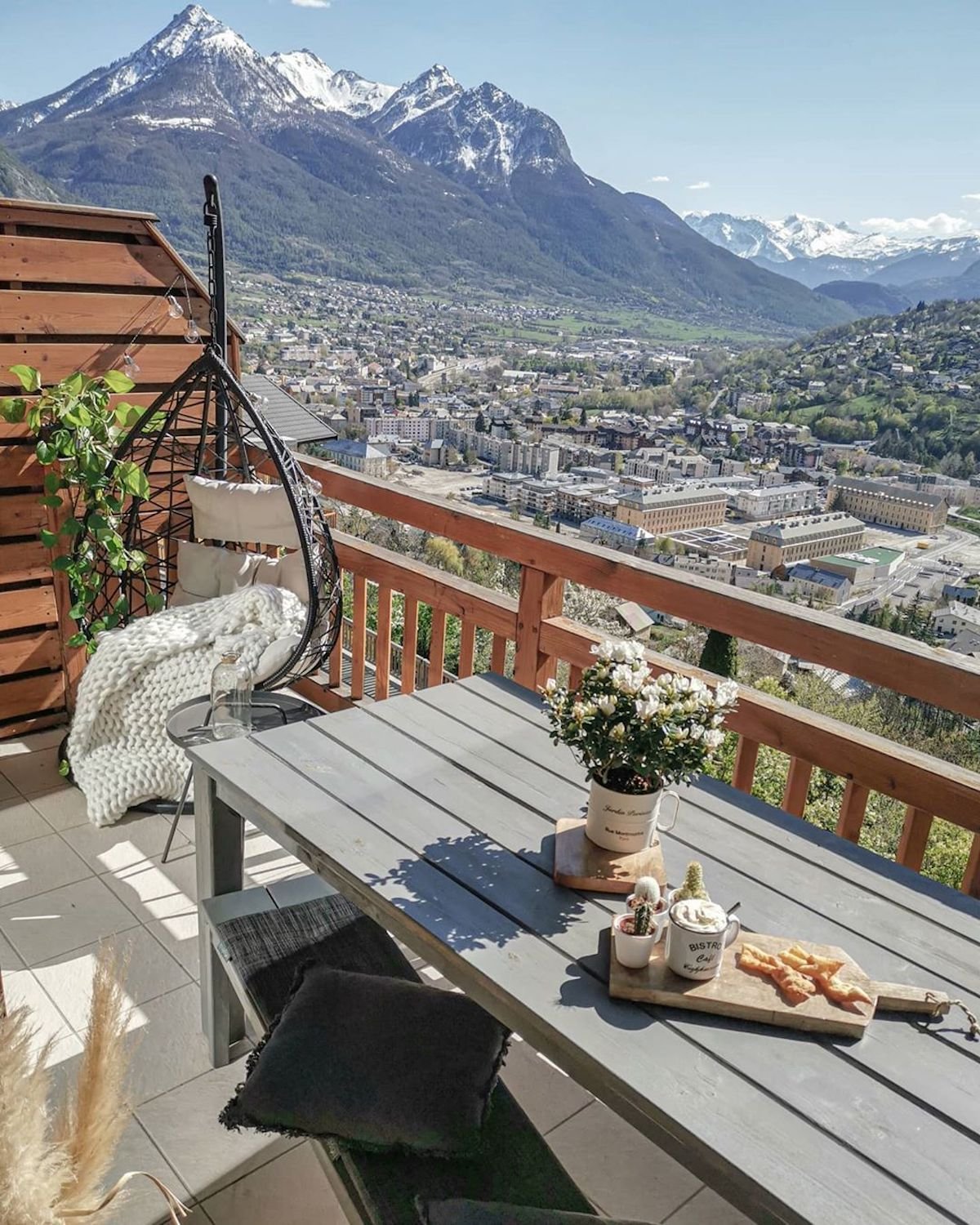 balcon table bois noir fauteuil suspendu rotin coussin lin - blog déco - clematc