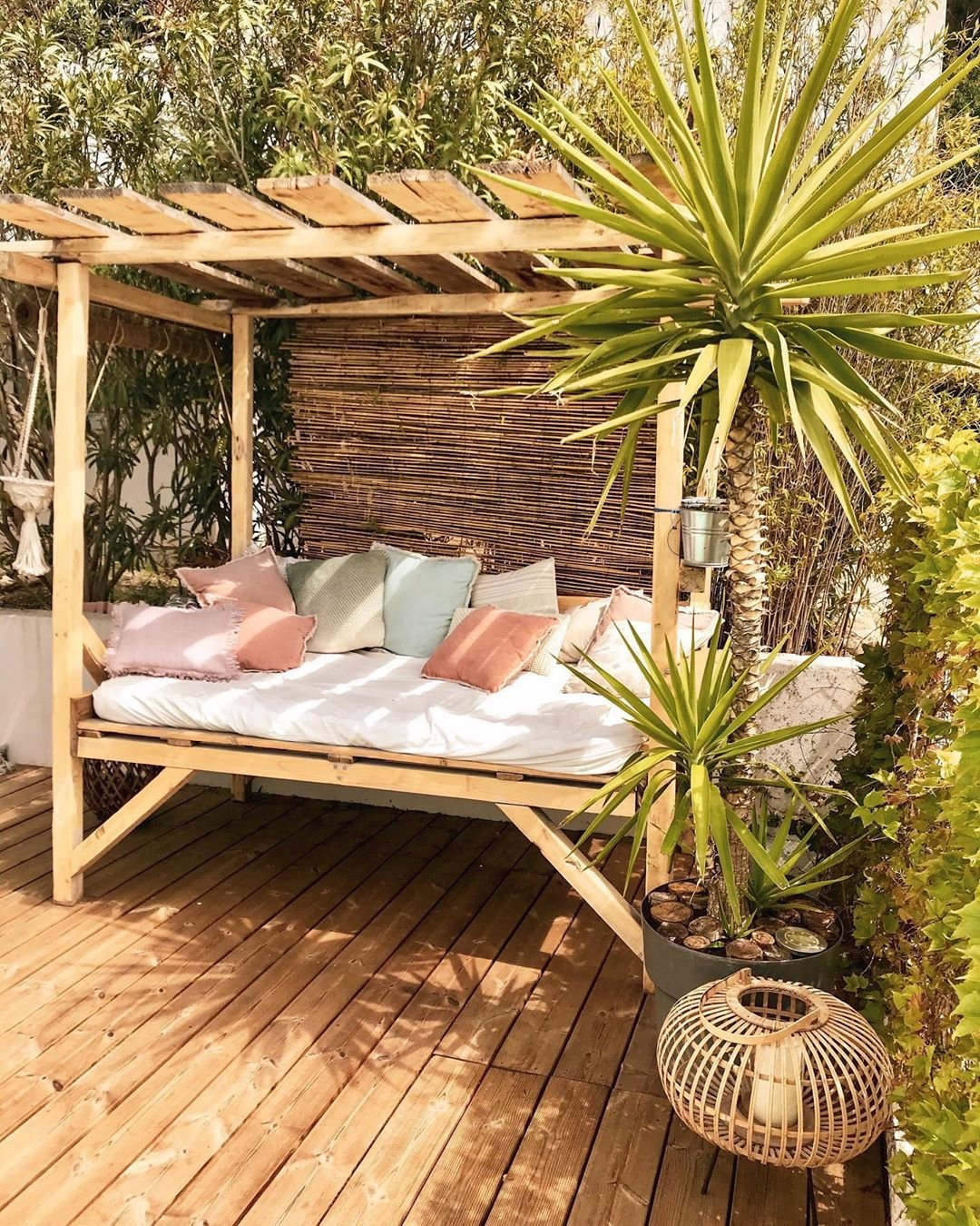 salon de jardin banquette en bois coussins rose bleu vert pastel palmier lanterne bois