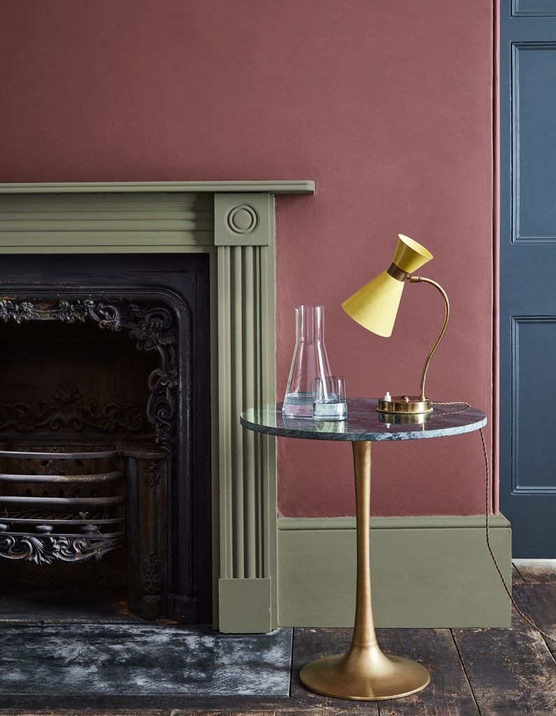 salon rustique cheminée vert kaki mur terracotta table basse ronde laiton marbre noir