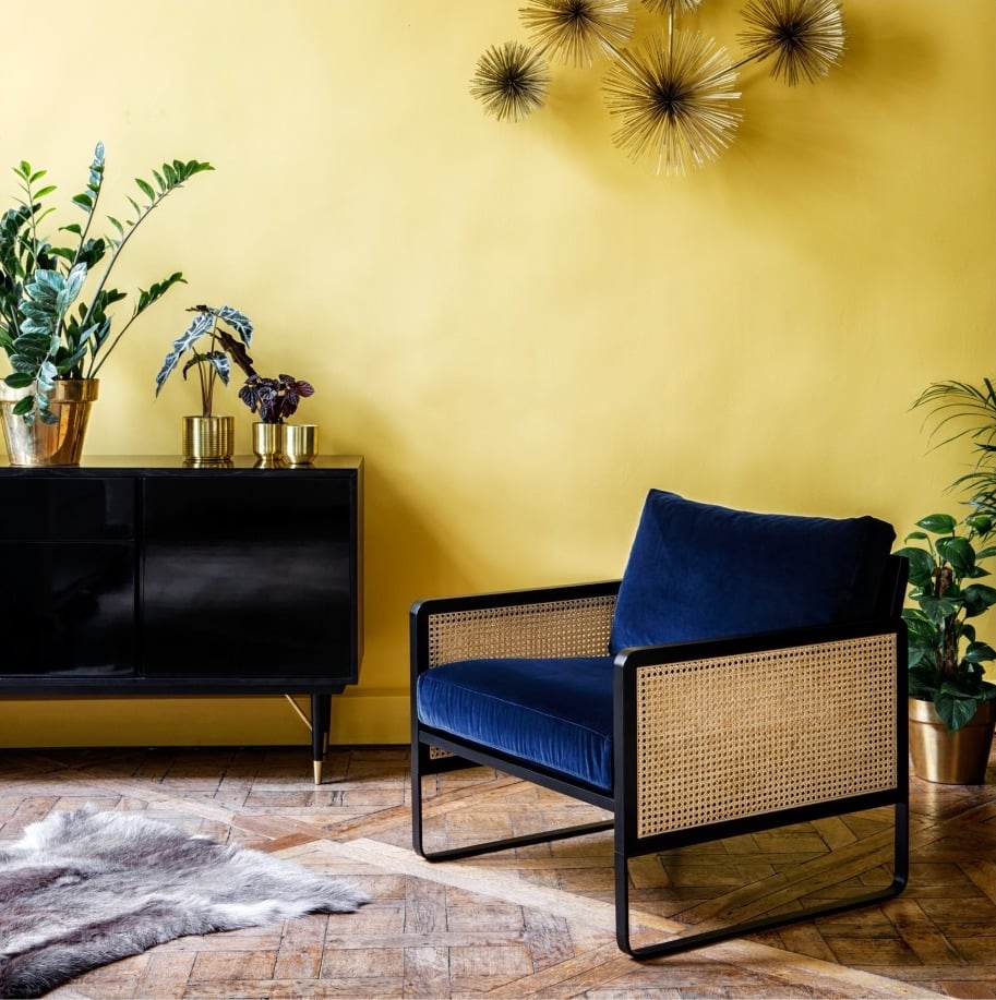 salon lumineux estival mur jaune fauteuil bleu velours accoudoir cannage