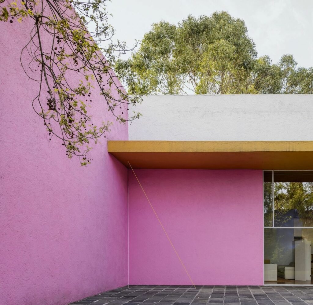 mur rose jaune sol pierres plates grises architecture