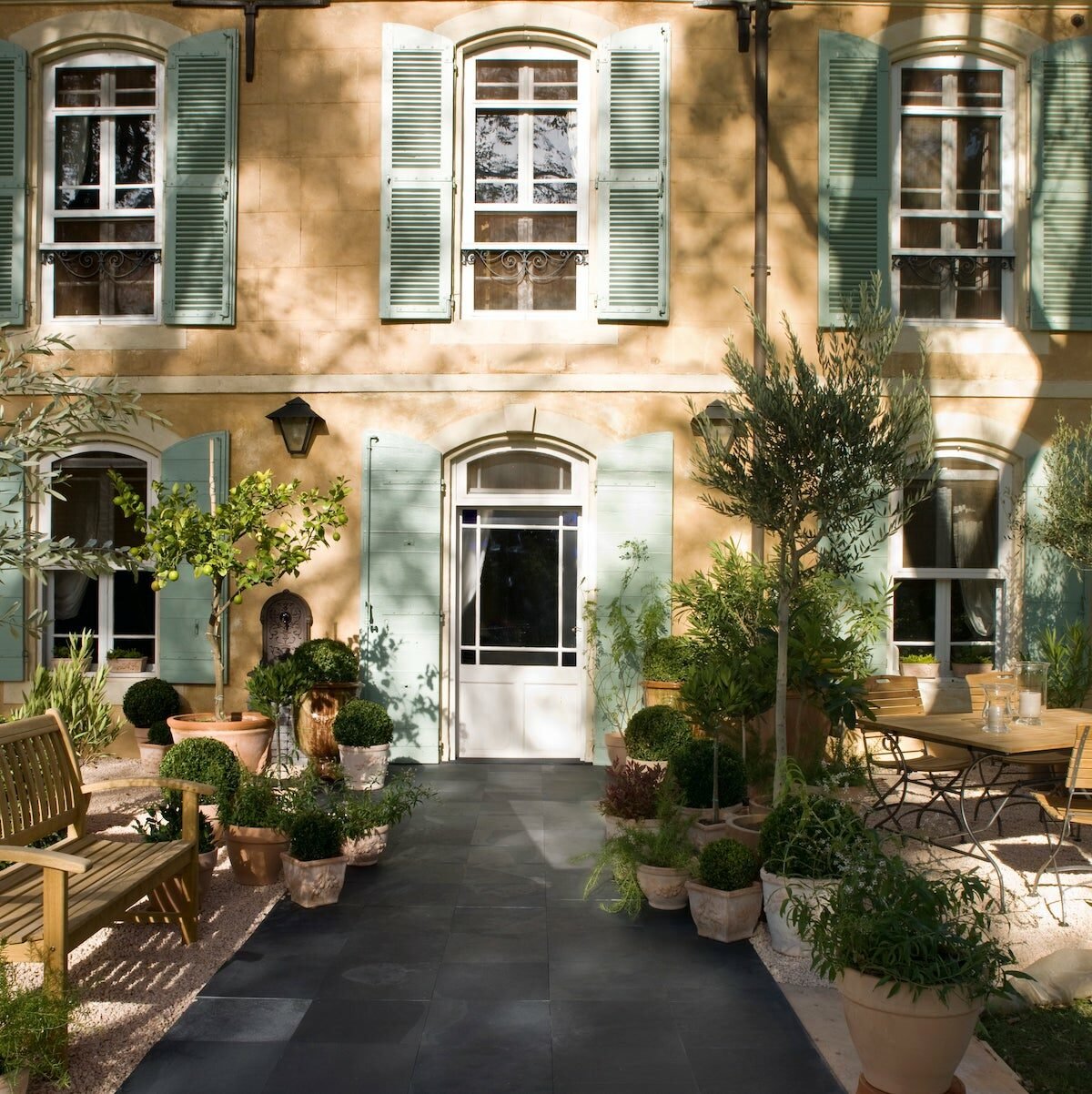 terrasse noire carre maison volet bleu pastel banc bois buisson