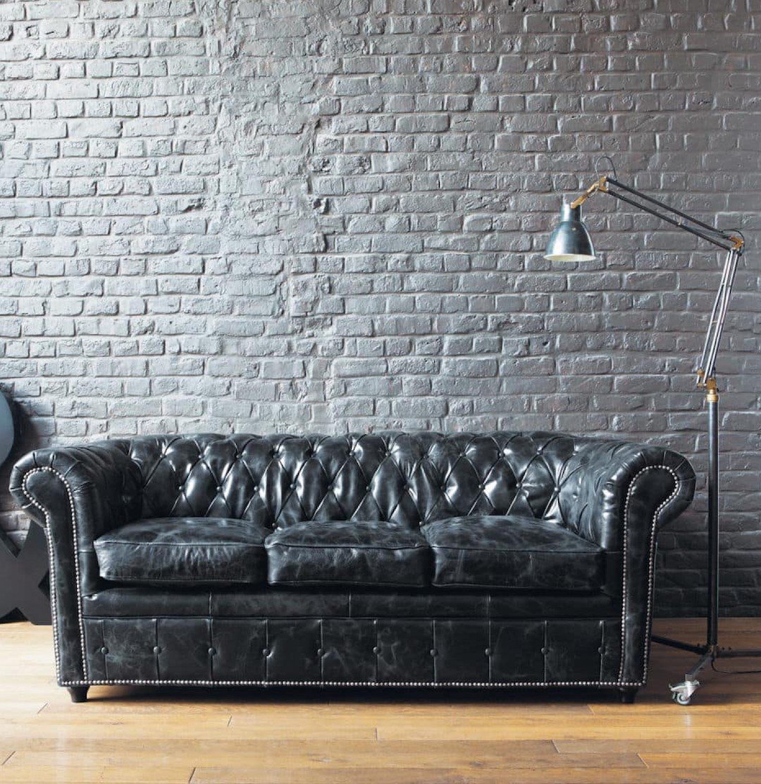 salon industriel mur briques blanches canapé droit noir