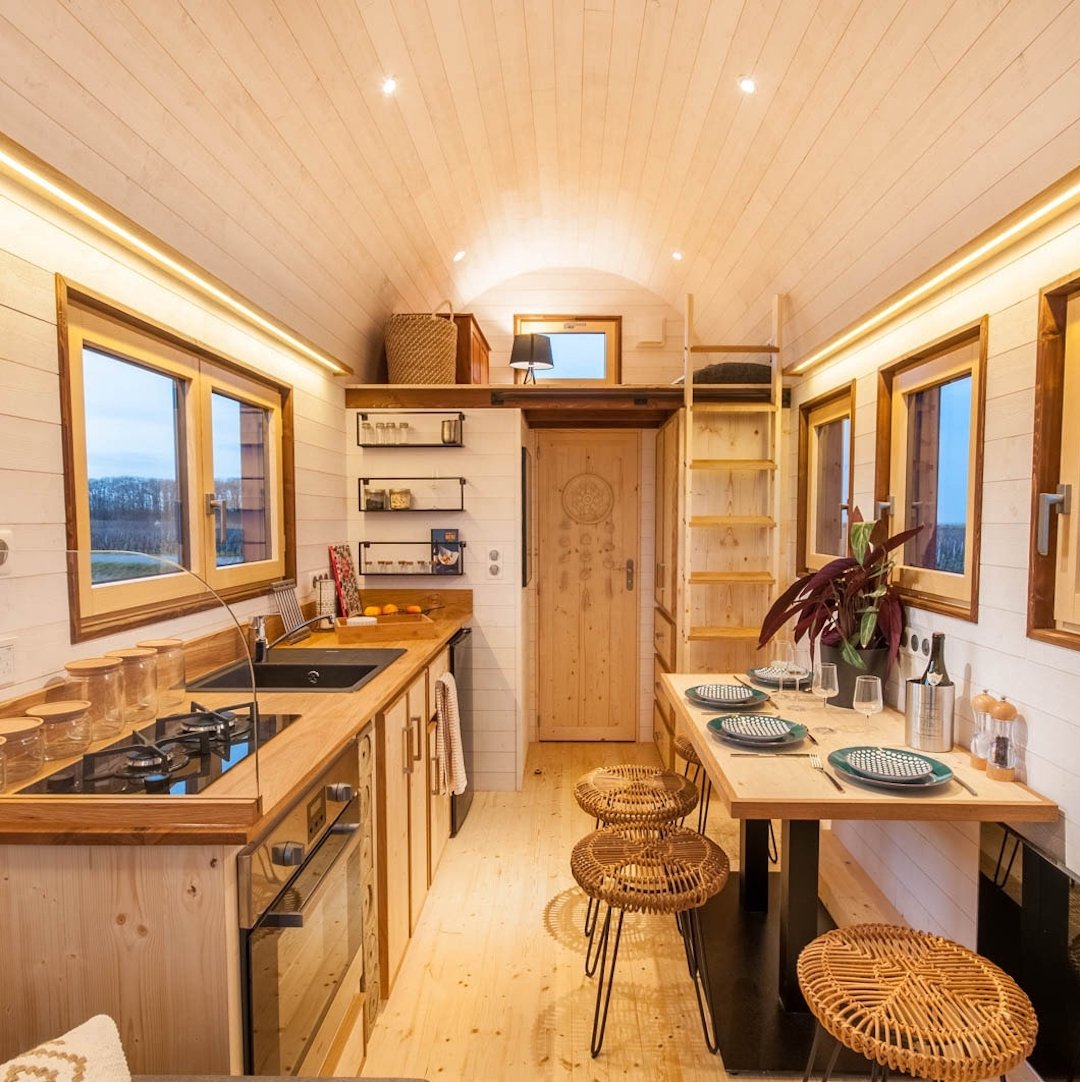 cuisine tiny house spacieuse équipée plan de travail bois espace de rangement table à manger tabouret osier