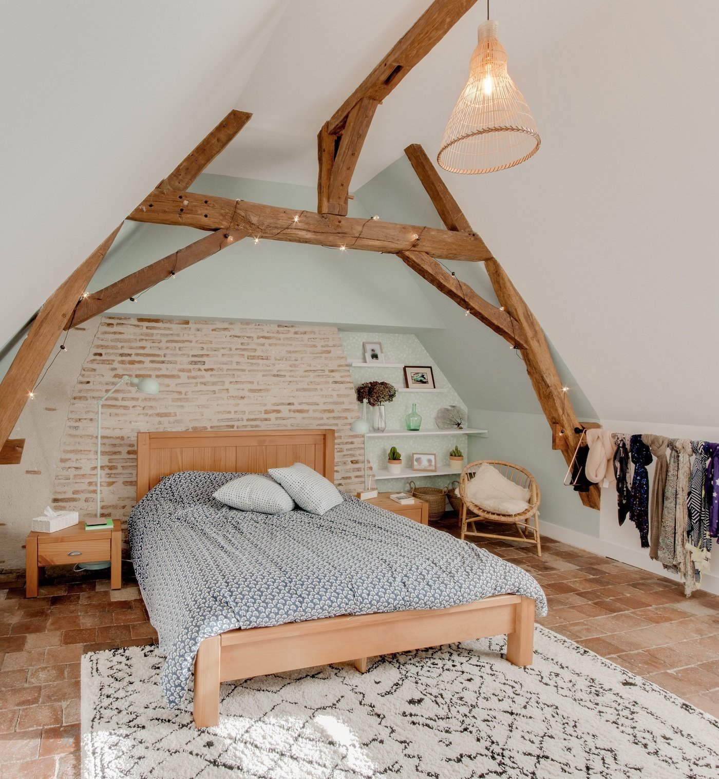 lit sous combles mur blanc poutre bois tapis berbère noir sol pierre orange