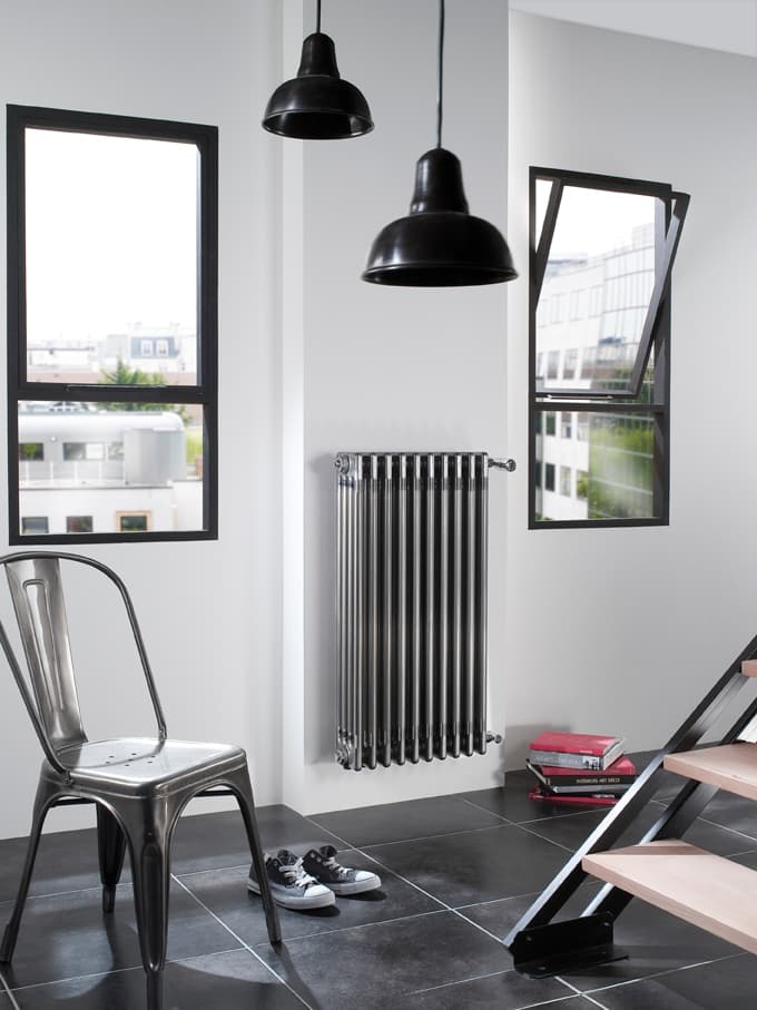 Radiateur Acova blanc dans un salon industriel aux murs gris et au mobilier en cuir