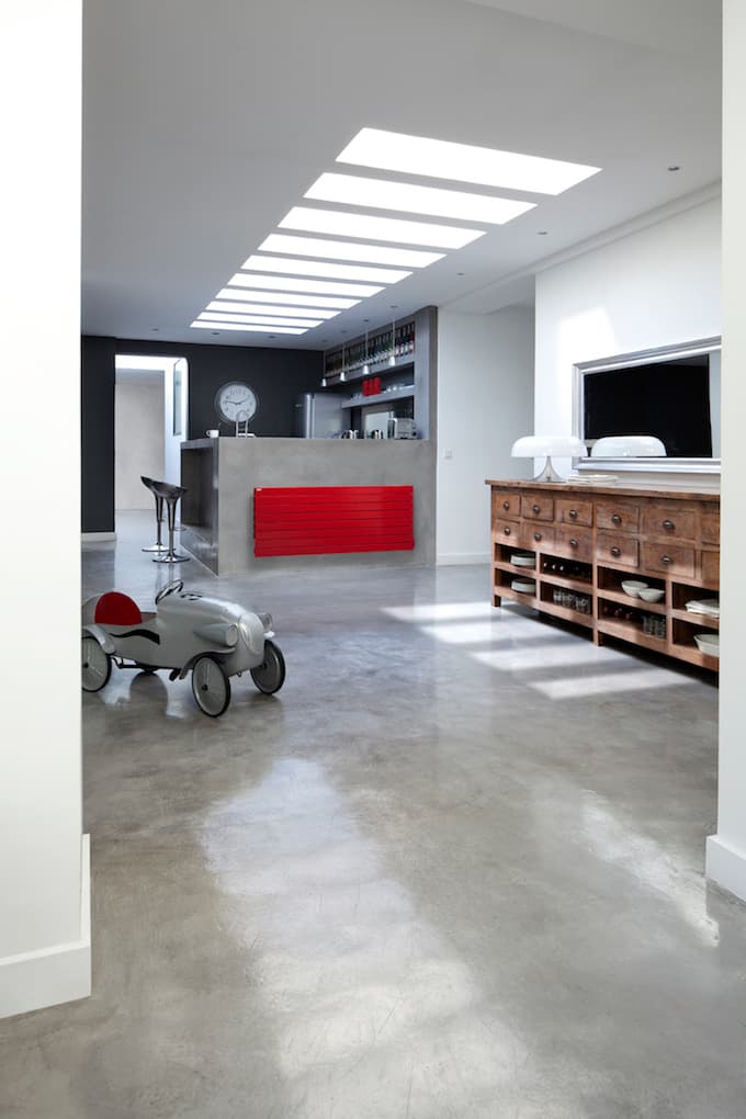 Radiateur horizontal rouge dans un loft aux murs en béton et au mobilier contemporain