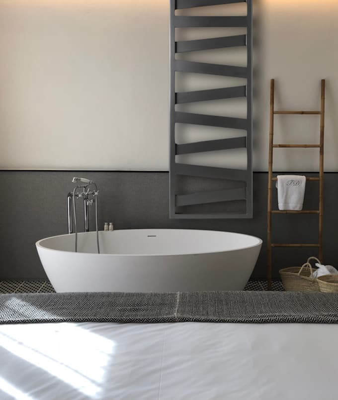 Radiateur sèche-serviettes Kazeane anthracite près d’une baignoire dans une salle de bain naturelle