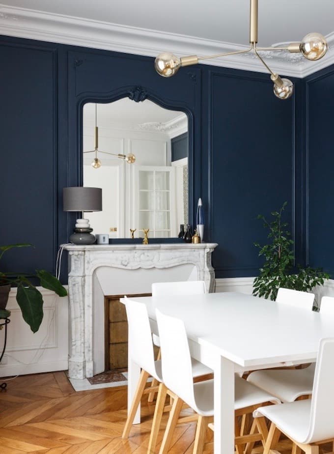 salle a manger Haussmann mur bleu foncé farrow cheminée marbre gris meuble blanc 