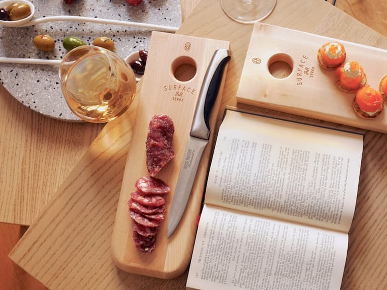 Planche en bois garnie de saucisson et petites coupelles pour l’apéritif