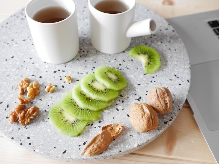 Tasse de thé, kiwi et noix composant une pause gourmande sur un plateau