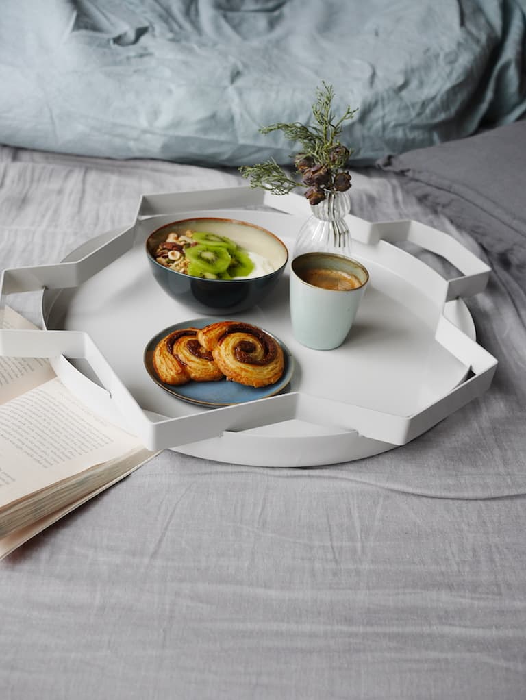 Petit déjeuner au lit avec granola, café et vaisselle bleue sur du linge en lin
