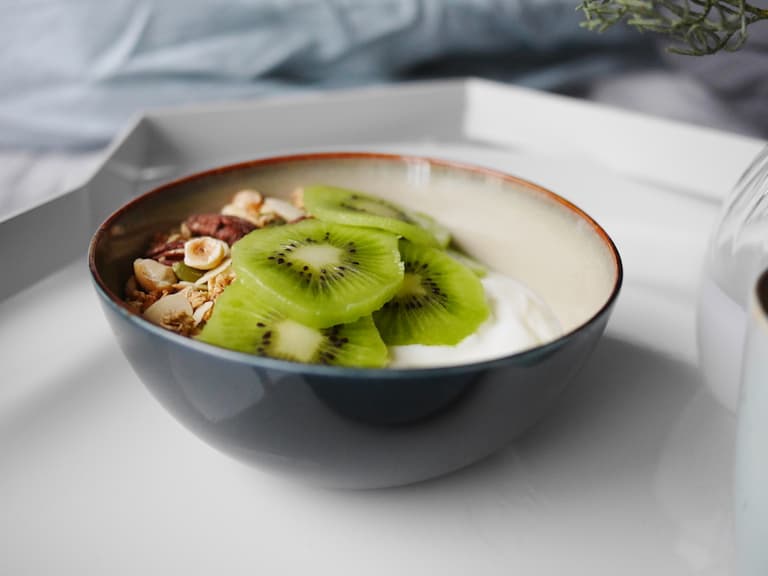 Bol de granola aux kiwis et tasse en céramique pour un petit déjeuner au lit