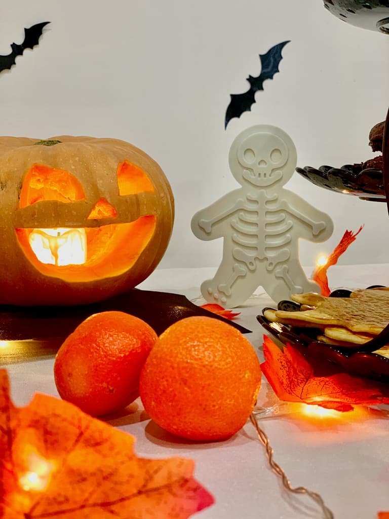 biscuits squelettes, bonbons, clémentines et guirlande lumineuse sur la table d'Halloween