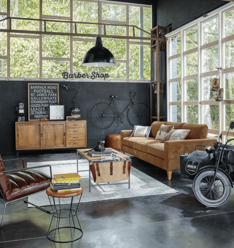 Salon industriel avec canapé gris, verrière, fauteuil en cuir et bicyclette