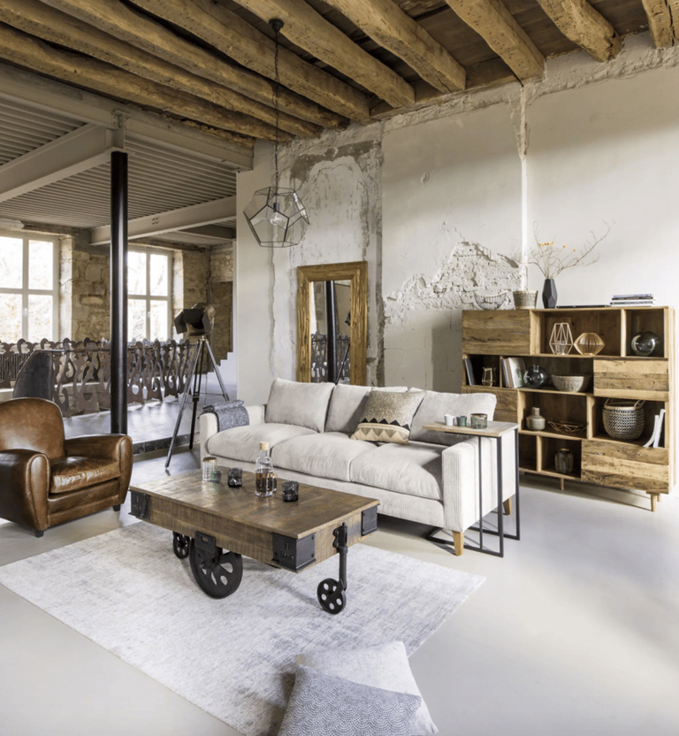 Salon de style industriel avec canapé gris, fauteuil en cuir et table basse en bois