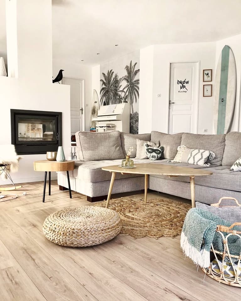 Salon avec canapé d’angle gris, table basse en bois et décoration inspirée du surf