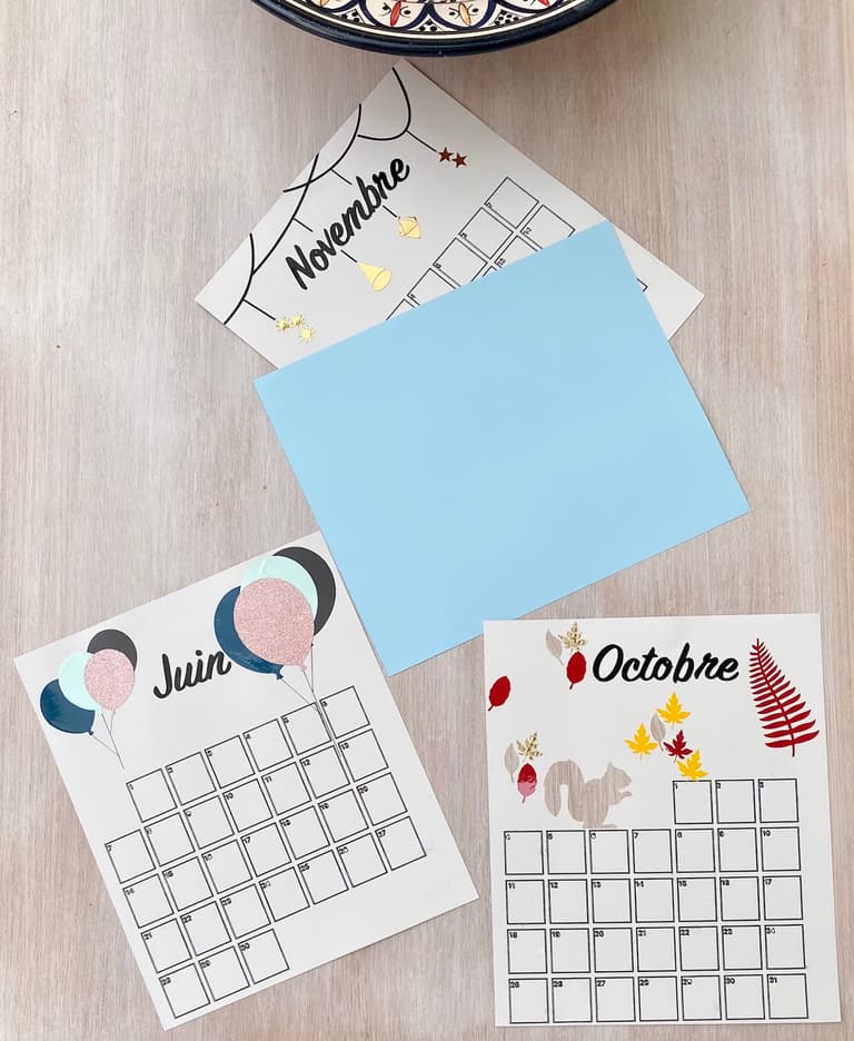 Pages de calendrier pour juin et octobre posées sur une table avec une feuille cartonnée bleue
