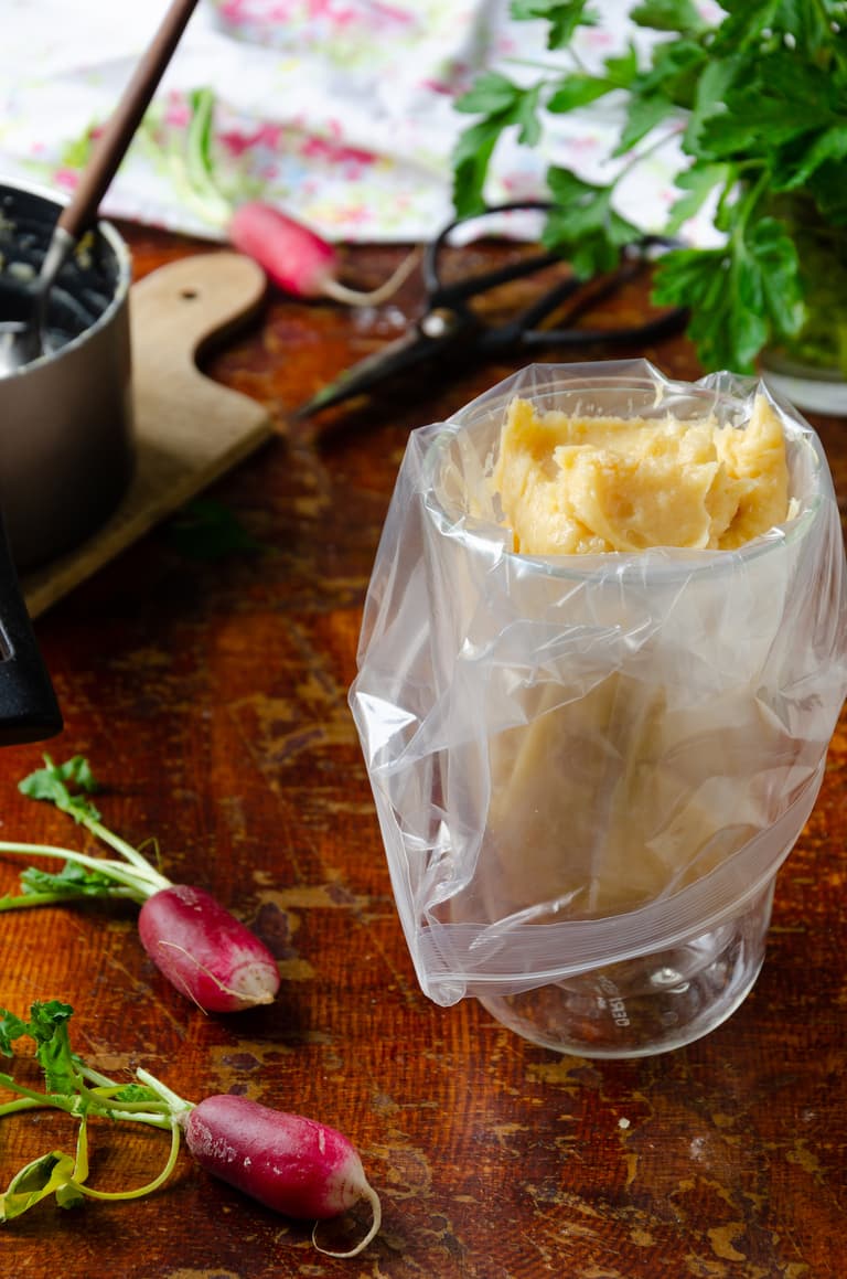Pâte à choux versée dans une poche à douille maintenue par un verre