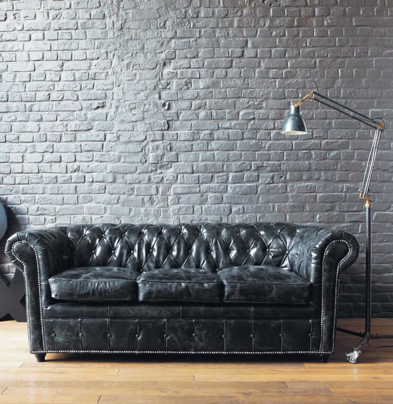 salon industriel mur briques blanches canapé droit noir