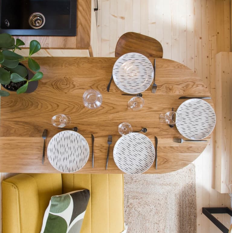 table à manger bois ovale assiette ronde noir et blanche plante verte tabouret