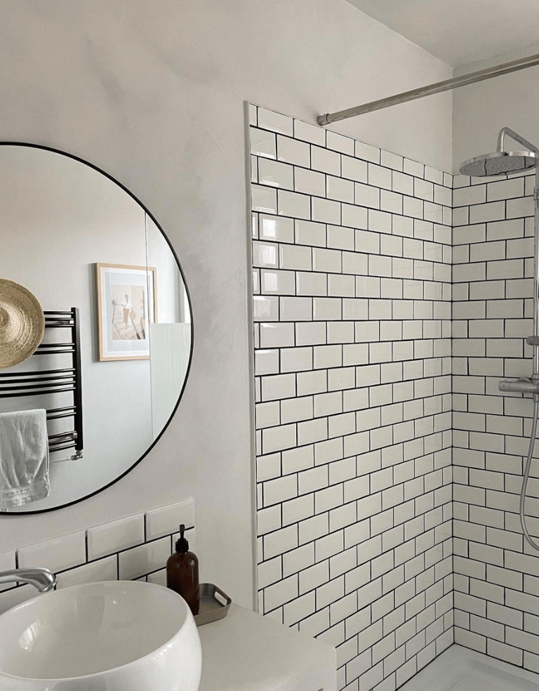 Salle de bain avec carrelage blanc et miroir rond