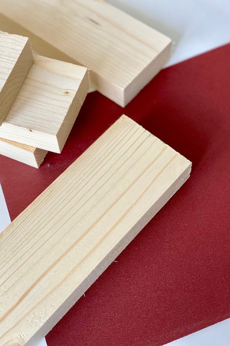 Morceaux de tasseau en pin posés sur une feuille de papier abrasif rouge après la découpe