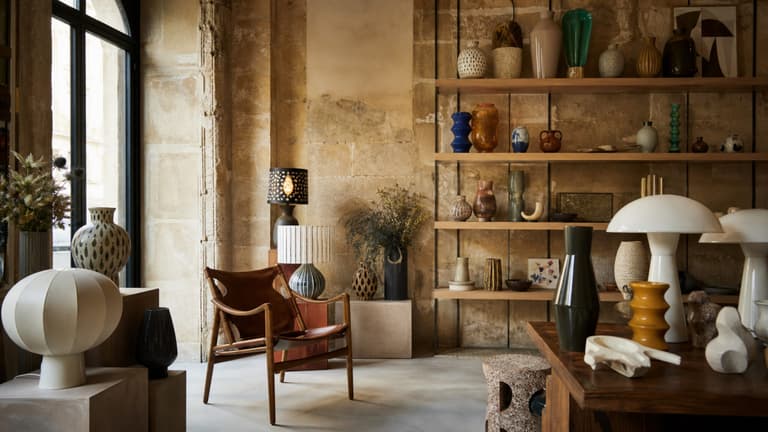 bonnes adresses déco à Bordeaux avec boutique design dans un intérieur en pierre blonde, étagères en bois, céramiques, lampes sculpturales et fauteuil vintage
