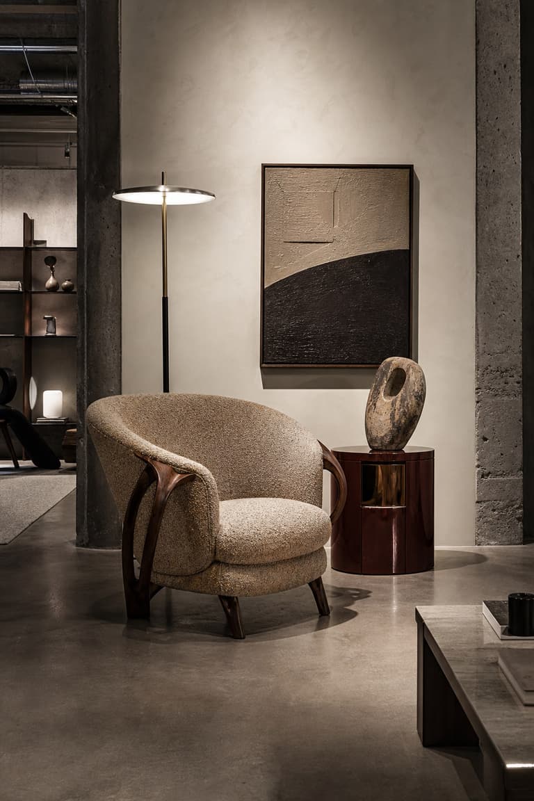galerie design à Milan avec fauteuil vintage sculptural, lampadaire contemporain, table laquée, vase et œuvre abstraite