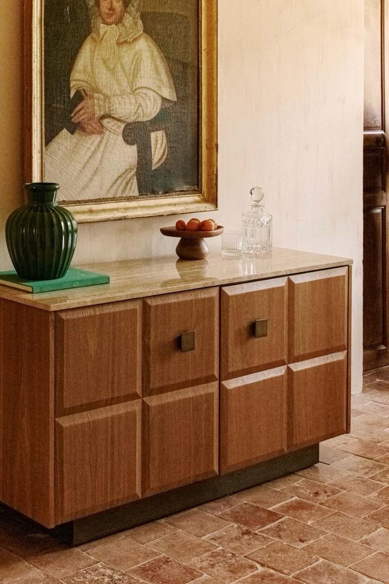 buffet en bois avec plateau en travertin, façades sculptées et objets décoratifs dans un intérieur contemporain