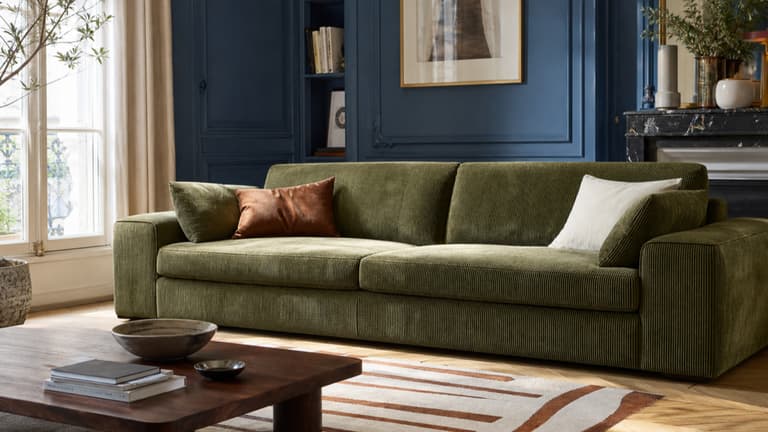 Canapé en velours côtelé vert olive dans un salon parisien aux murs bleu profond