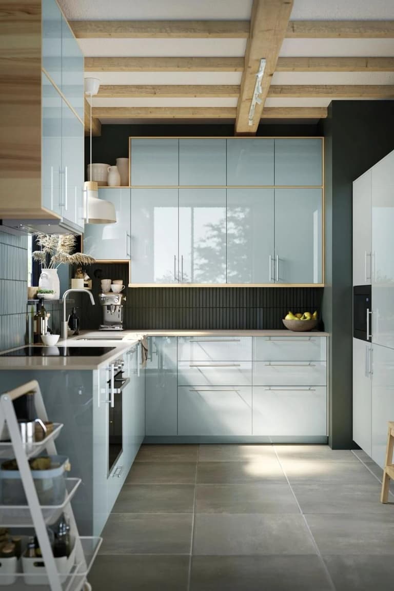 Cuisine vert pâle très lumineuse avec plan de travail clair, grandes fenêtres et poutres apparentes