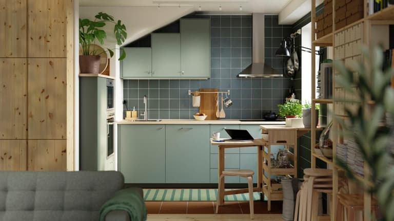 Cuisine ouverte vert sauge avec plan de travail clair, crédence vert-gris et rangements en bois clair