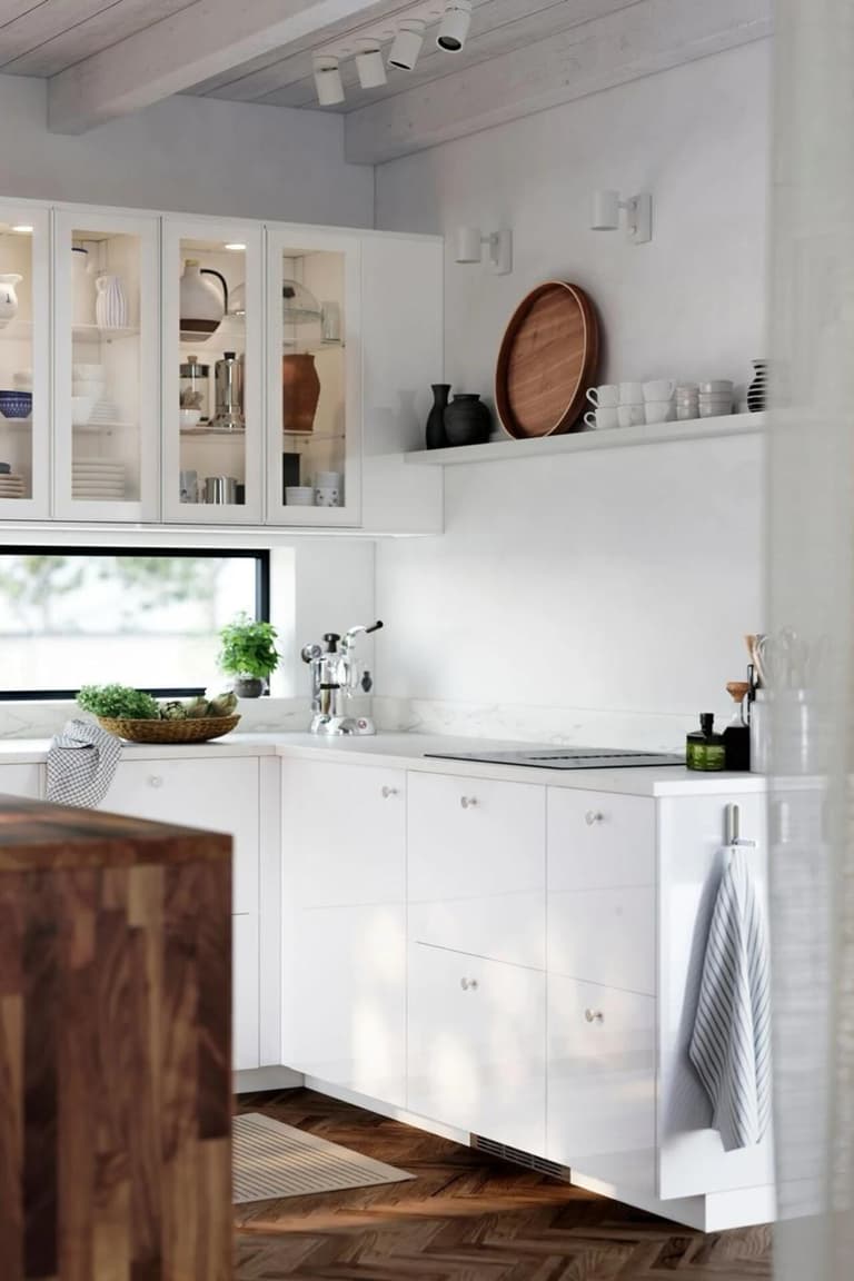 Cuisine blanche lumineuse avec plan de travail clair, évier sous fenêtre et îlot en bois