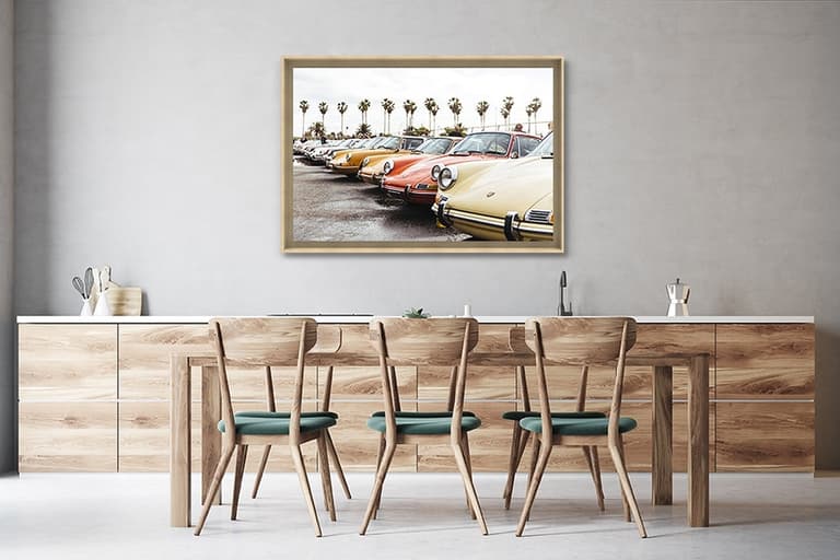 Photographie de Porsche anciennes encadrée au-dessus d’une grande table en bois dans une salle à manger contemporaine