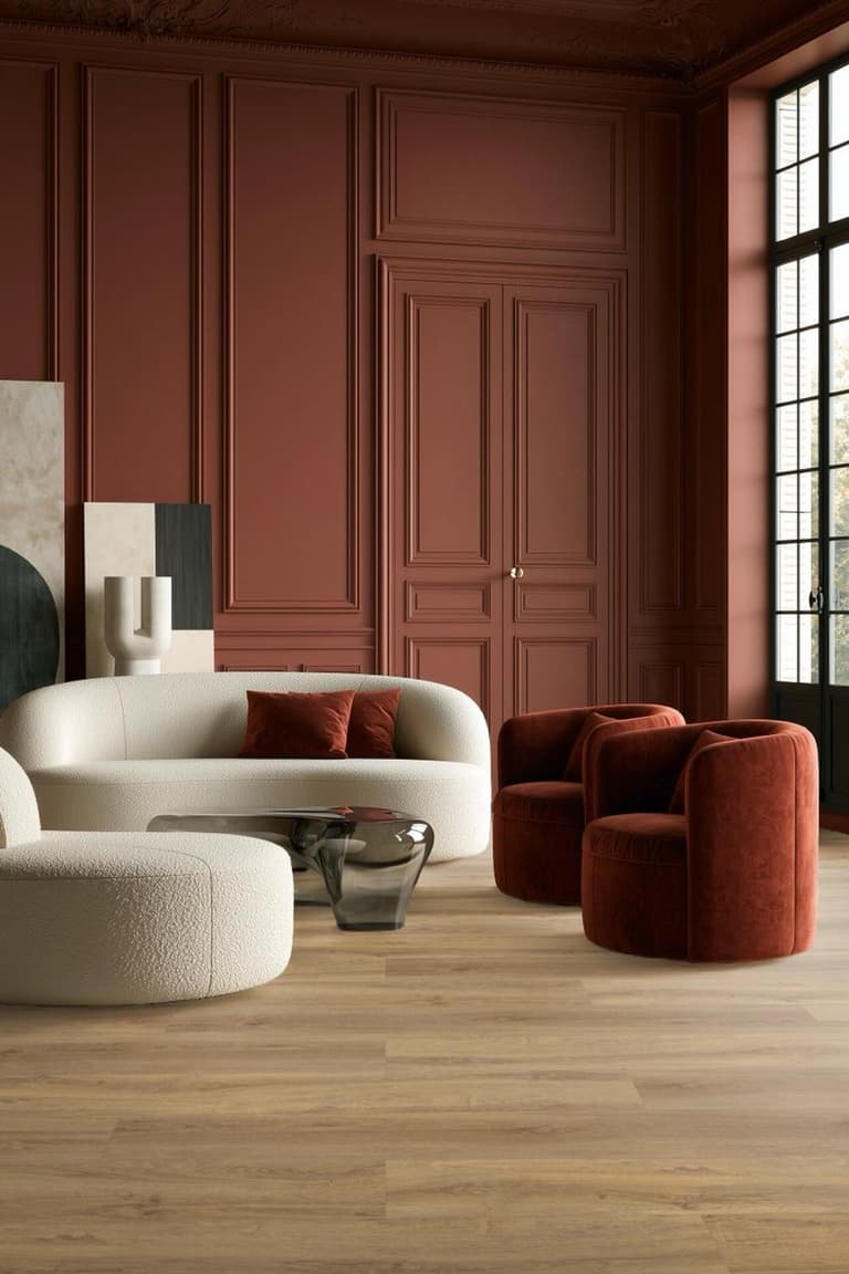 Salon rouge bordeaux avec moulures, fauteuils en velours rouille, canapés écrus et parquet clair