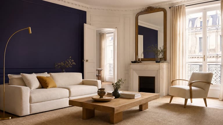 Salon parisien lumineux avec mur violet profond, canapé écru, bois clair et touche moutarde.