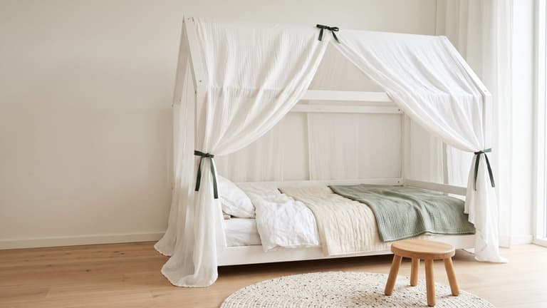 Lit KURA transformé en lit cabane avec rideaux en gaze crème dans une chambre d’enfant