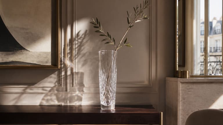 Vase en cristal transparent posé sur une console en bois dans un intérieur contemporain