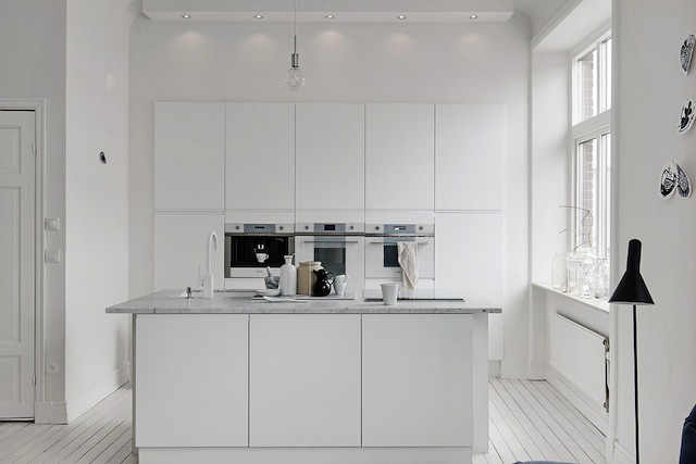 Une cuisine blanche minimaliste épurée encastrée ilot central table de cuisson aspirante