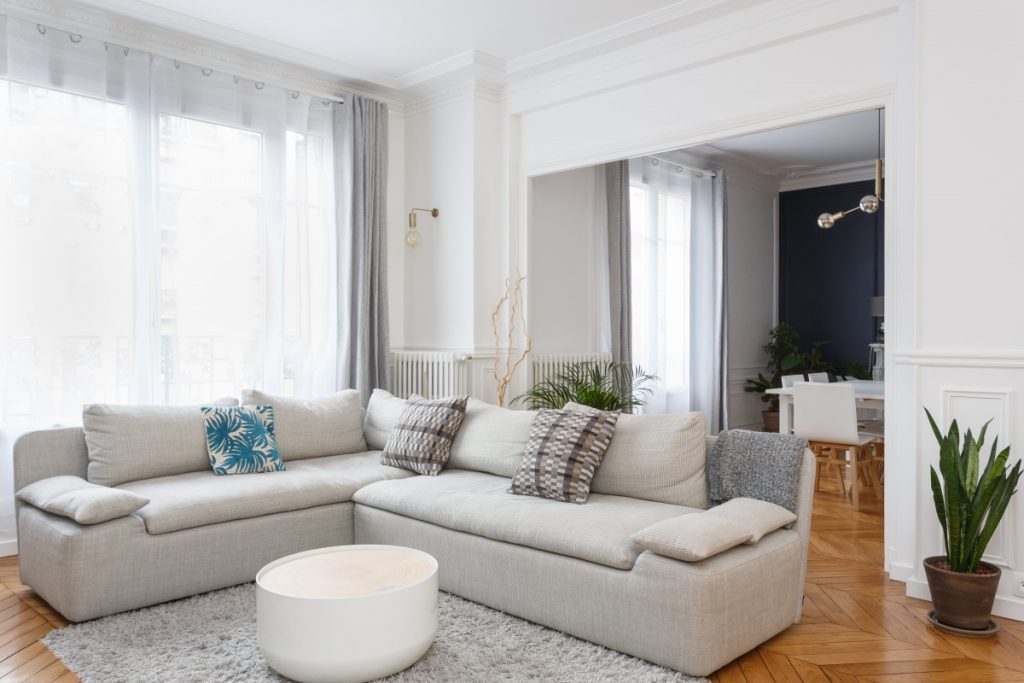 appartement chic parisien salon séjour canapé gris parquet bois table-basse ronde voilage blanc rideaux gris plante verte - blog déco - clemaroundthecorner
