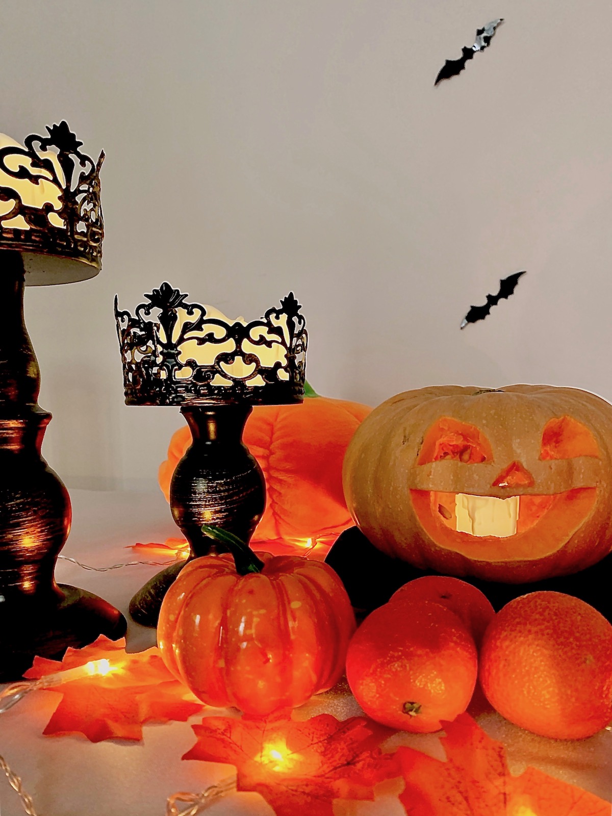 chandelier noir, clémentines, feuillages d'automne et chauves-souris murales pour Halloween